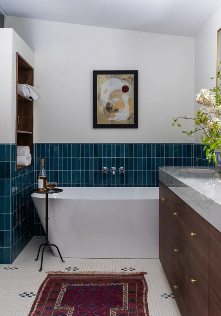 Bathroom with white painted walls and blue tile with bathtub and white tile floor with rug 1